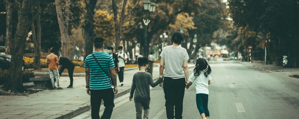 A family walks down a street from behind.