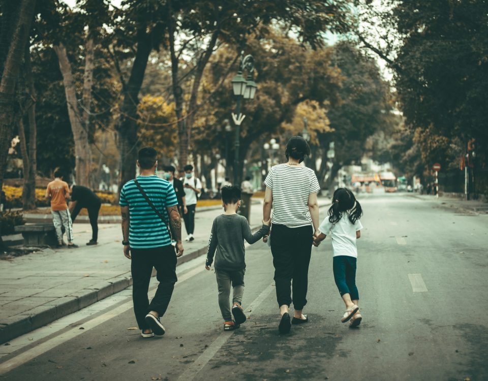 A family walks down a street from behind.