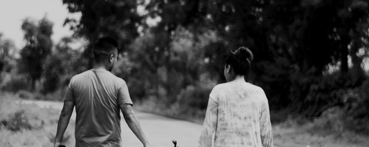 A man and woman walk holding a toddler's hands.