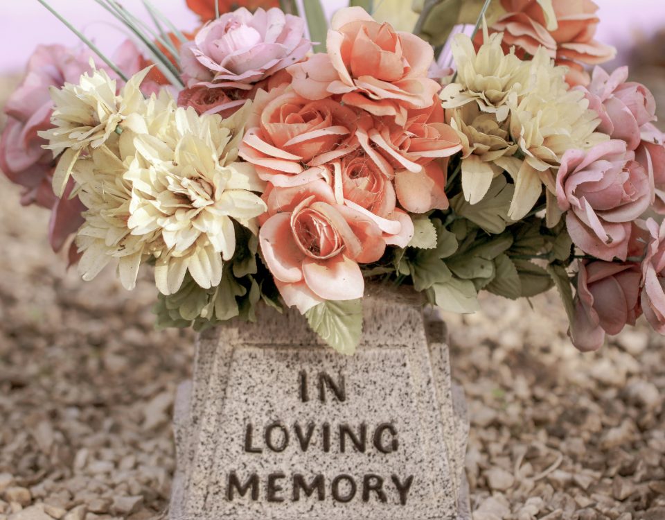A headstone that says in loving memory with flowers.
