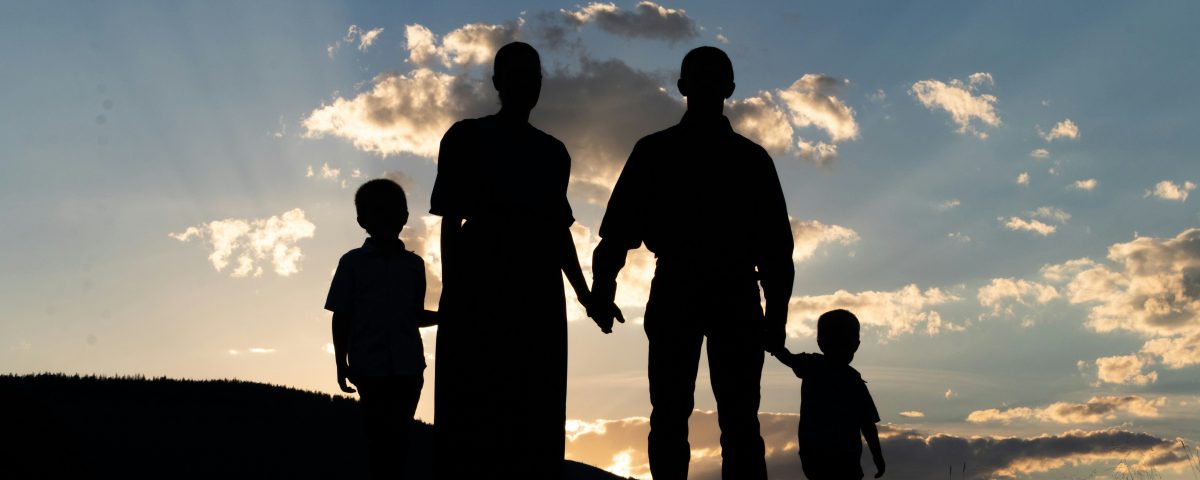 A family stands on a mountain at sunrise.