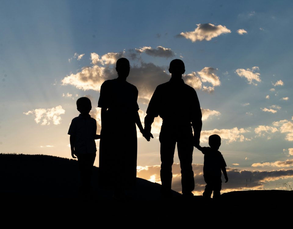 A family stands on a mountain at sunrise.