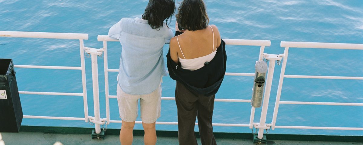 A couple looks into the water over a railing.