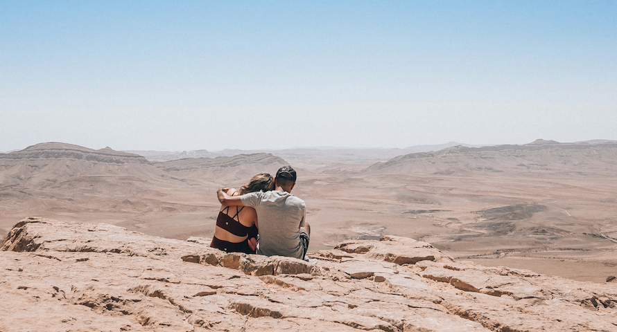 A couple sits in the desert.