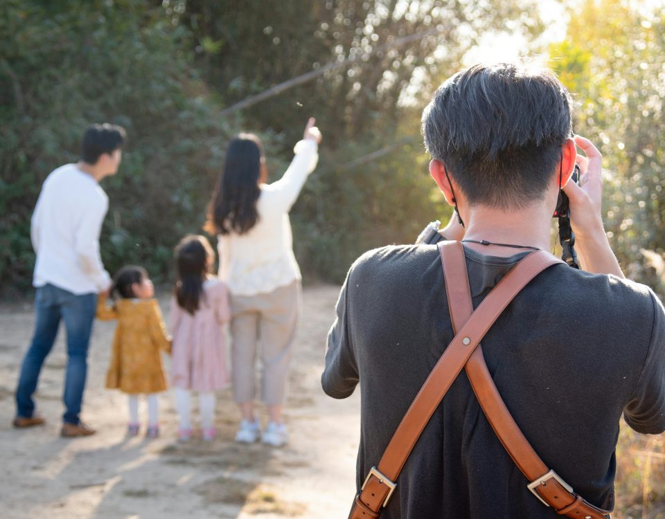 A man takes a photo of his family from behind.