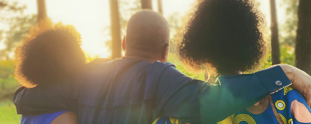 Black people from behind with their arms around each other.