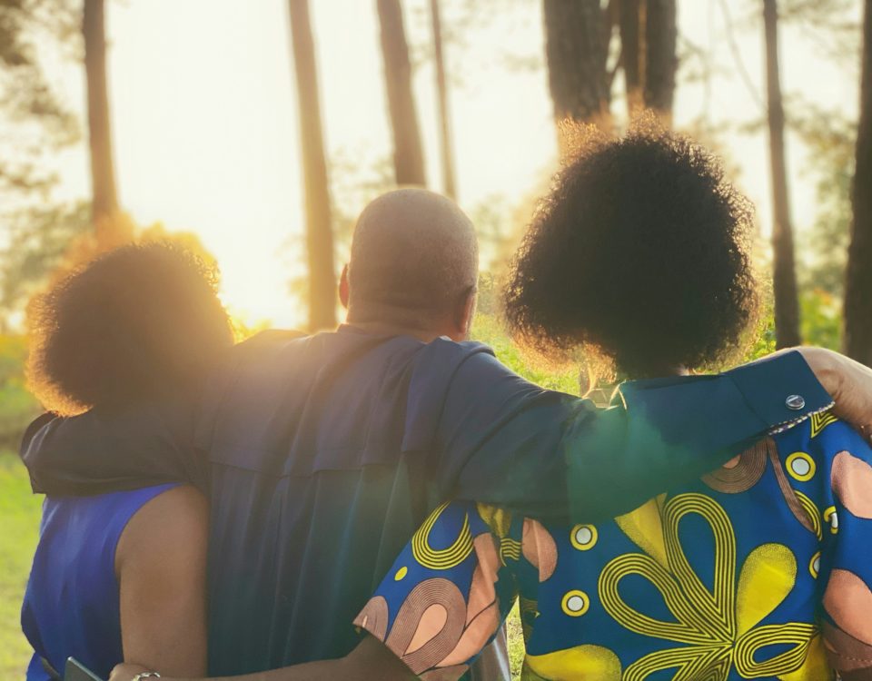 Black people from behind with their arms around each other.