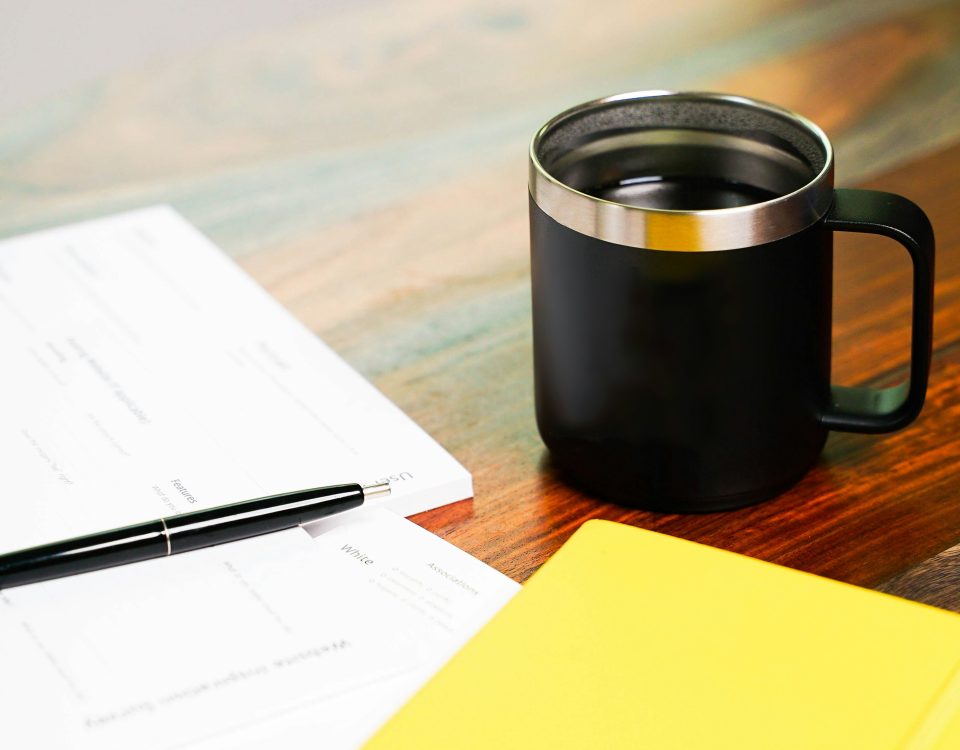 Papers and a folder sit by a cup of coffee.