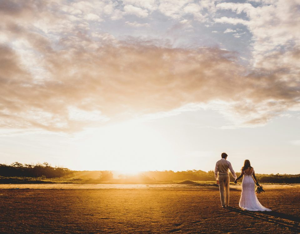 A bride and groom walk in a field.