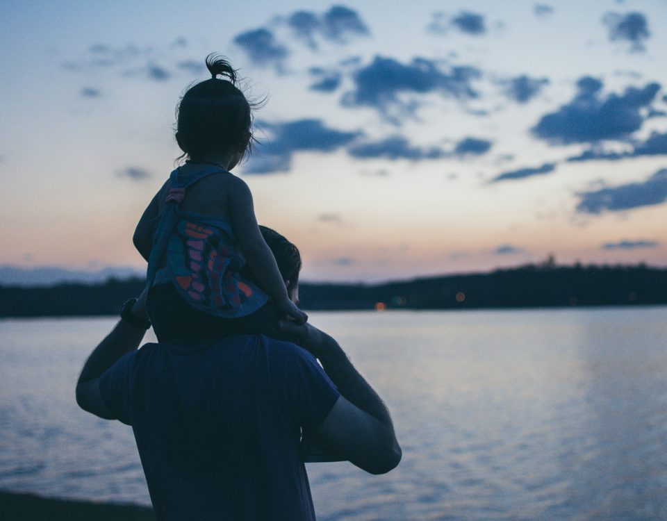 A man holds a little girl on his shoulders.